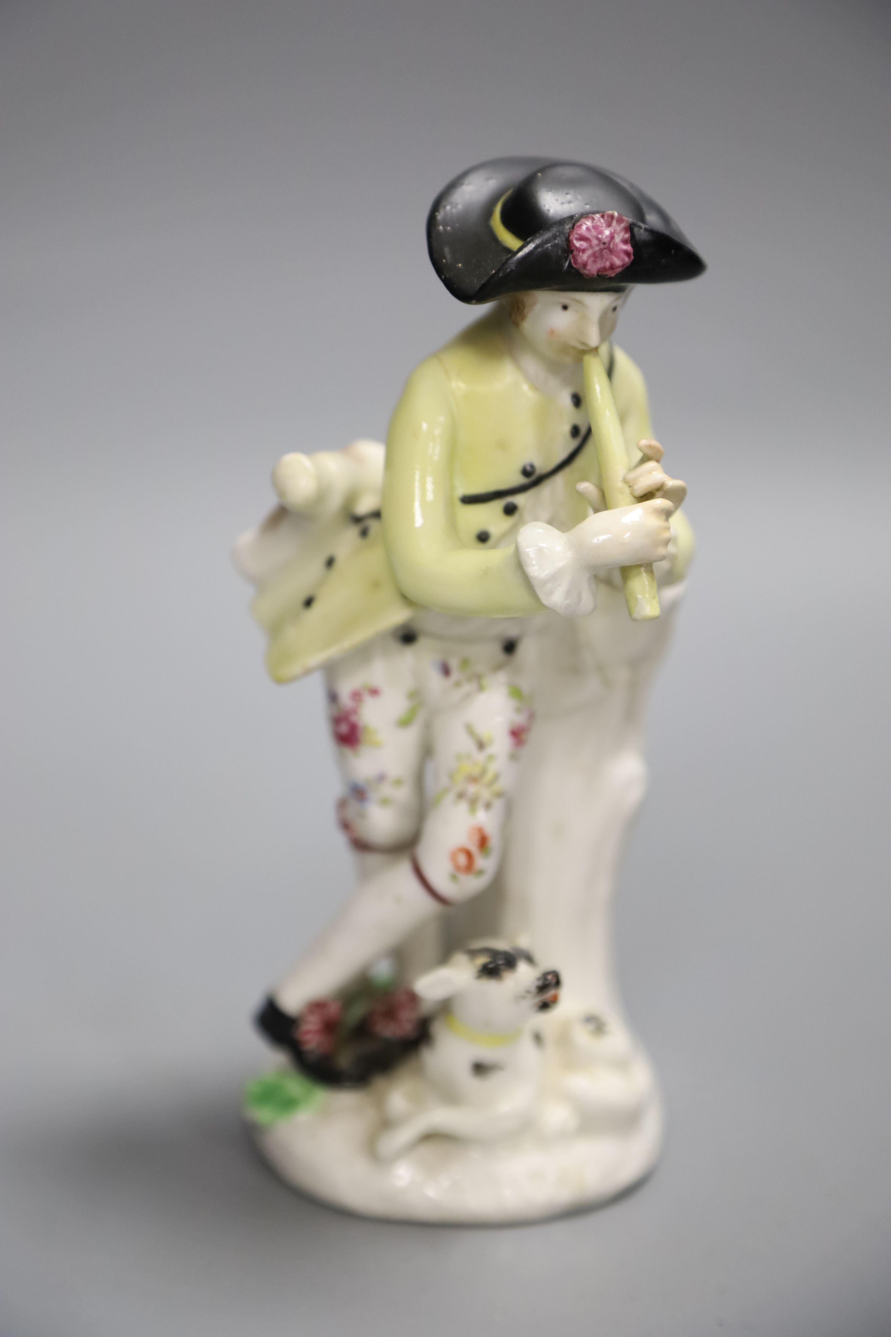 An 18th century Bow figure of a piper with dog after a Meissen model by J.J. Kaendler, height 15cm
